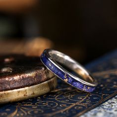 two wedding rings sitting on top of a blue and gold plated table with intricate designs