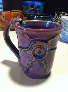 a close up of a coffee cup on a table with other cups in the background