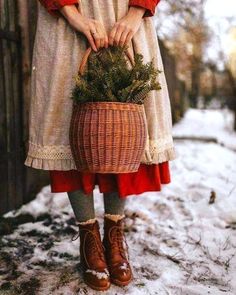 a woman holding a basket full of plants in the snow