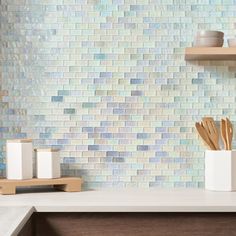 a kitchen counter with wooden utensils and white containers on it, next to a blue mosaic tile backsplash