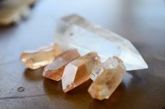 three different colored crystals sitting on top of a wooden table next to an orange and white object