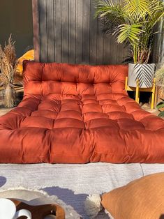 an orange futon bed sitting on top of a white rug