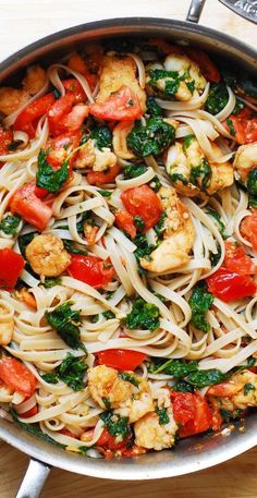 a pan filled with pasta and vegetables on top of a wooden table