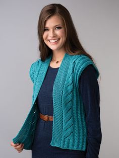 a woman wearing a blue sweater and cardigan posing for the camera with her hands in her pockets