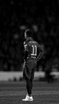 a black and white photo of a man standing on the field with his hands in his pockets