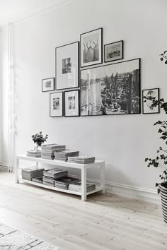 a living room with white walls and pictures on the wall, including a coffee table