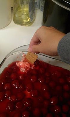 someone is dipping something into a cranberry sauce