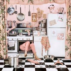 a woman sitting on the floor in front of an oven with pots and pans