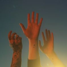 two hands reaching up into the air with sun shining on them and blue sky in background