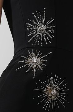 a woman wearing a black dress with silver stars on the front and back, as well as