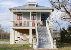 a white house with stairs leading up to the front door and second story on stilts