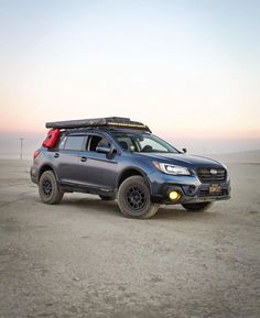 a car with a surfboard strapped to it's roof parked in the desert