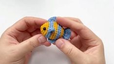 a person holding a small crocheted fish in their hands