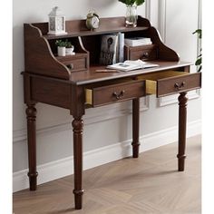 a wooden desk with two drawers and a mirror on the wall above it, in front of a window