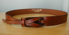 a brown leather belt sitting on top of a wooden table