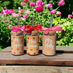 three mason jars with pink hearts are sitting on a table in front of some flowers