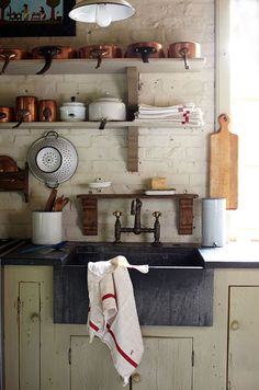 an old kitchen sink with pots and pans on the shelves