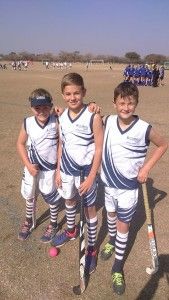 three young boys in uniforms standing next to each other with baseball bats and balls on the ground