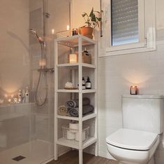 a white toilet sitting in a bathroom next to a walk in shower with shelves above it