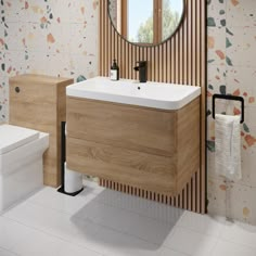 a white toilet sitting next to a bathroom sink under a round mirror on a wall