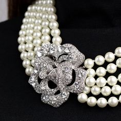 Product Description: Inspired by Audrey Hepburn's "Breakfast at Tiffany's" iconic look, this piece consists of five rows of decadent glass pearls which meet with a stunning rhinestone flower clasp. USA-made.   Dimensions: 18" L, 10 Millimeter Pearls  ﻿Style Number: ﻿9082N Tiffany Pearl Necklace, Tiffany Pearls, Clear Crystal Bracelet, Pearl Trend, Pearl And Diamond Necklace, Breakfast At Tiffany's, Pearl Pin, Clasp Necklace, Rhinestone Flower