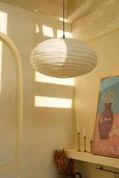 a white light fixture hanging from the ceiling in a room with a painting on it