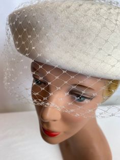 "This hat is a few shades of white or should I say off white? It's very retry, a felted wool base with semi structured netting in the front. A kind of ornamental centerpiece on the top.  It looks very nice. Under closer inspection, it does have some minor issues. A couple moth nibbles it appears, and a tiny spot or 2. I did lint roll it and brush it a little gently, but it's a white so it likely isn't as white as it once was, it's hard to say.  The netting seems to be decent however I did notice White Cloche Hat With Short Brim For Wedding, White Short Brim Cloche Hat For Weddings, White Brimmed Felt Hat For Formal Occasions, Cream Cloche Hat For Evening, Elegant White Felt Hat For Winter, Winter Wedding Fascinator With Short Brim, Winter Wedding Felt Hat With Curved Brim, White Fitted Felt Hat, Elegant Cream Felt Hat For Formal Occasions