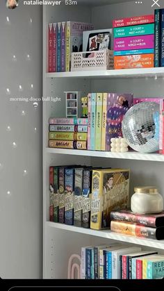 a book shelf filled with lots of books next to a wall mounted clock and other items