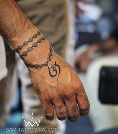 a man's hand with a tattoo on it and a chain around the wrist