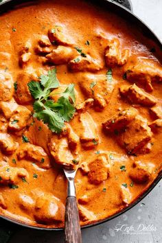 a skillet filled with chicken tikka and garnished with cilantro