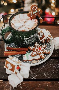 a cup of hot chocolate with marshmallows and gingerbread cookies on a plate