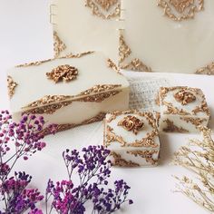 three pieces of cake sitting on top of a table next to flowers and an open book