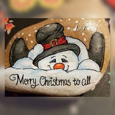 a snowman painted on the side of a rock with words merry christmas to all