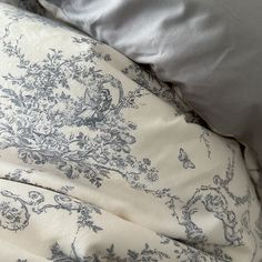 an unmade bed covered in blue and white linens with two pillows on top of it