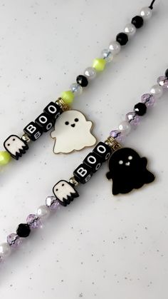 two black and white beads with ghost charms attached to them on a necklace that says boo boo