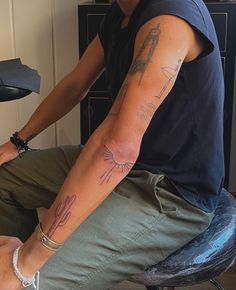 a man sitting on top of a chair with tattoos on his arm and hand next to him