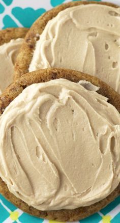 three cookies with frosting sitting on top of a blue and white table cloth next to each other