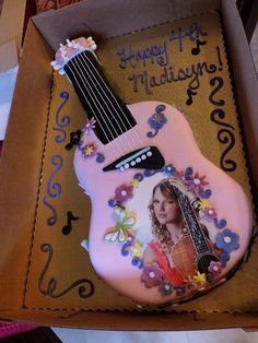 a birthday cake shaped like a guitar in a box with the image of a woman's face on it