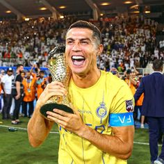 a man holding a trophy in front of a crowd at a soccer game with his mouth wide open