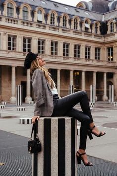 a woman sitting on top of a post in front of a building