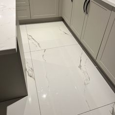 a white kitchen with marble flooring and counter tops in the middle of the room