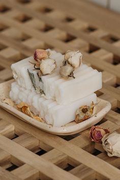 a square piece of soap sitting on top of a wooden table next to dried flowers