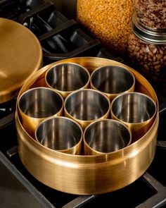 an assortment of metal cups sitting on top of a stove