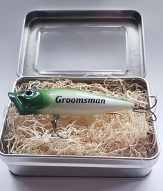 a green and white fishing lure in a metal box