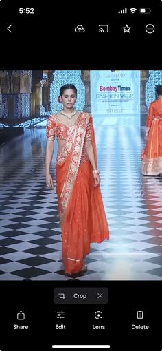 a woman in an orange sari walks down the runway