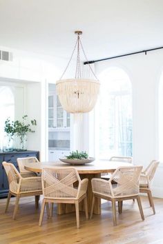 a dining room table with chairs and a chandelier hanging from it's ceiling