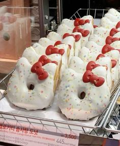 several donuts with white frosting and red bows are on display in a store