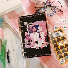 a pink and white table topped with notebooks, pens and eyeglasses on top of it