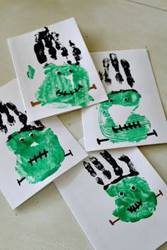 four children's handprints with green and black designs on them, sitting on a table