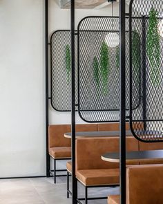 the inside of a restaurant with tables and chairs, plants on the wall behind them